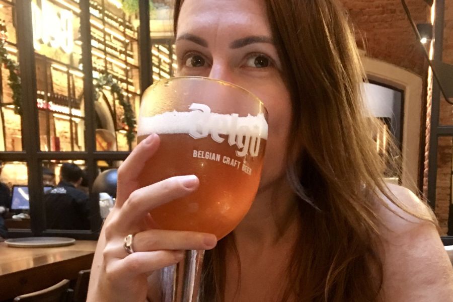 a woman drinks a large lager from a chalice glass in a bar