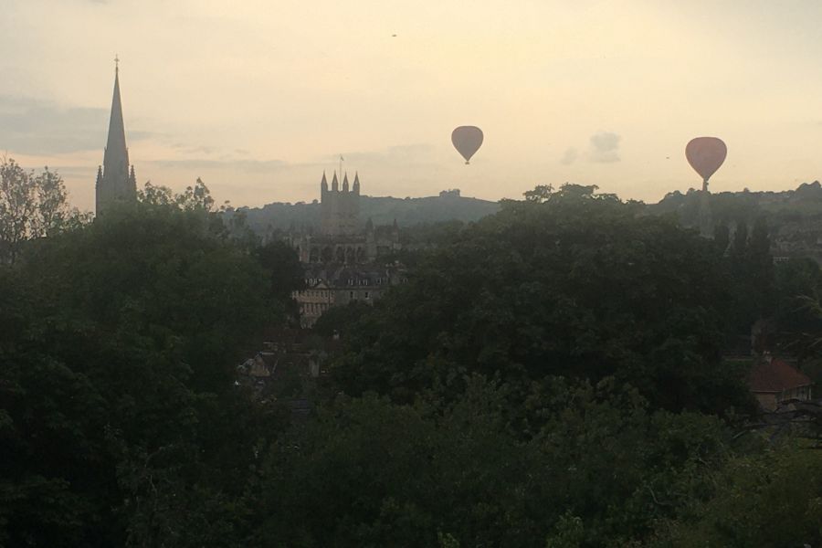 the bath skyline at sunset, featuring air balloons flying ober Bath abbey.