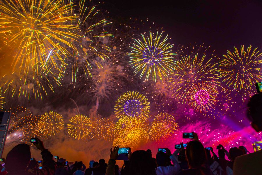 A large group of people filming an epic and colorfu firework display