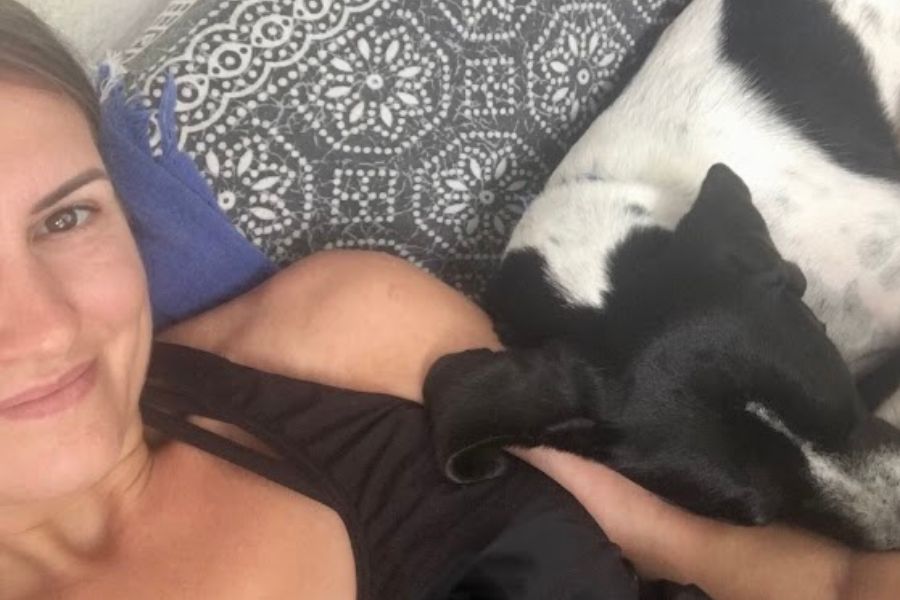 a pretty woman and a black and white dog take a selfie on a sofa in Costa Rica.