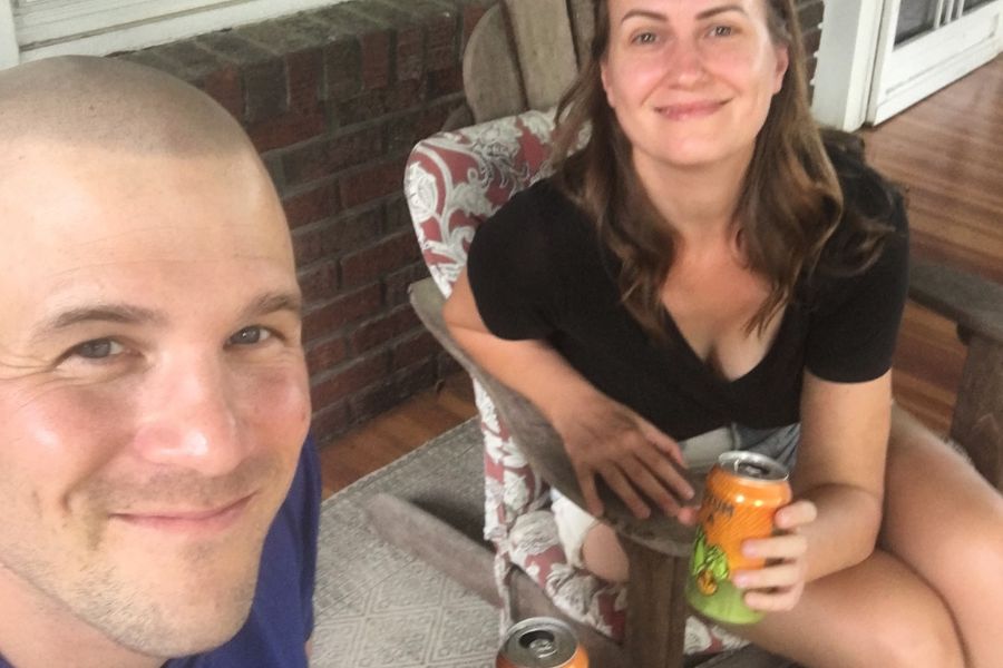 2 people drinking a beer on the front porch.