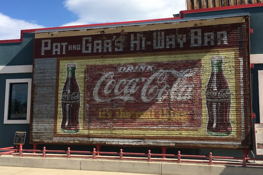 a retro 1950s Coca Cola billboard showing signs of its years of wear.