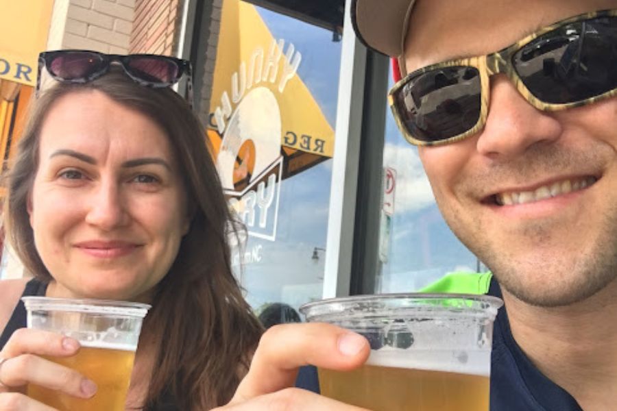 a man and a woman take a selfie while saluting with a beer each