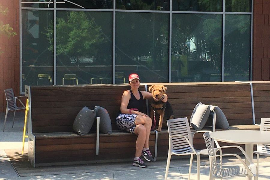 a woman and an Airedale dog pose for a nice selfie on a sunny day in a cafe's patio