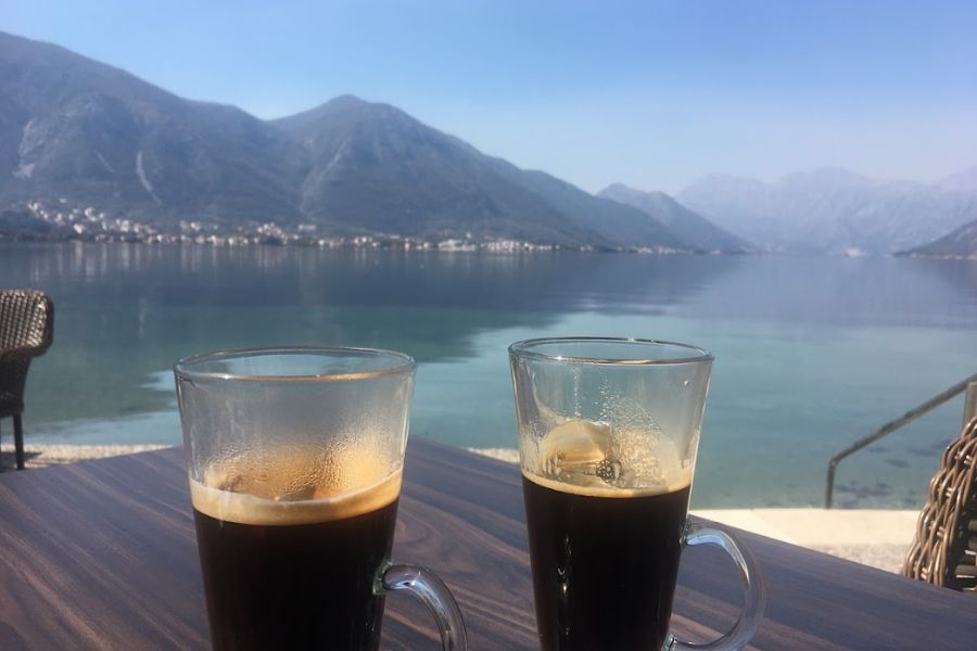 two black coffees in front of a stunning lake back drop with mountains and a scenic vista all the way to the ocean