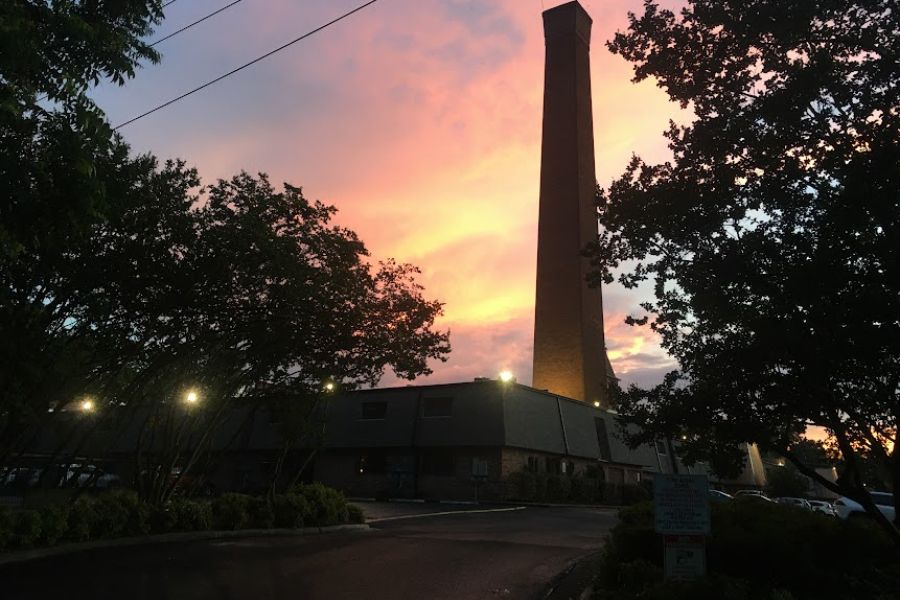 a tall chimney climbs high against a colorful sunset