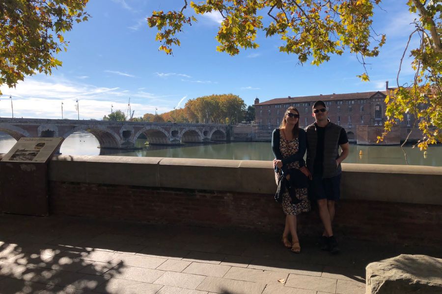 a man and a woman taking a selfie on the banks of the River Garrone, Pont Neuf in the distance