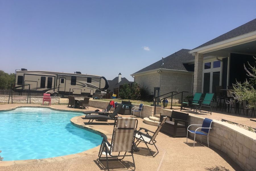 a nice garden pool with a large RV in the background and a bungalow house to the right