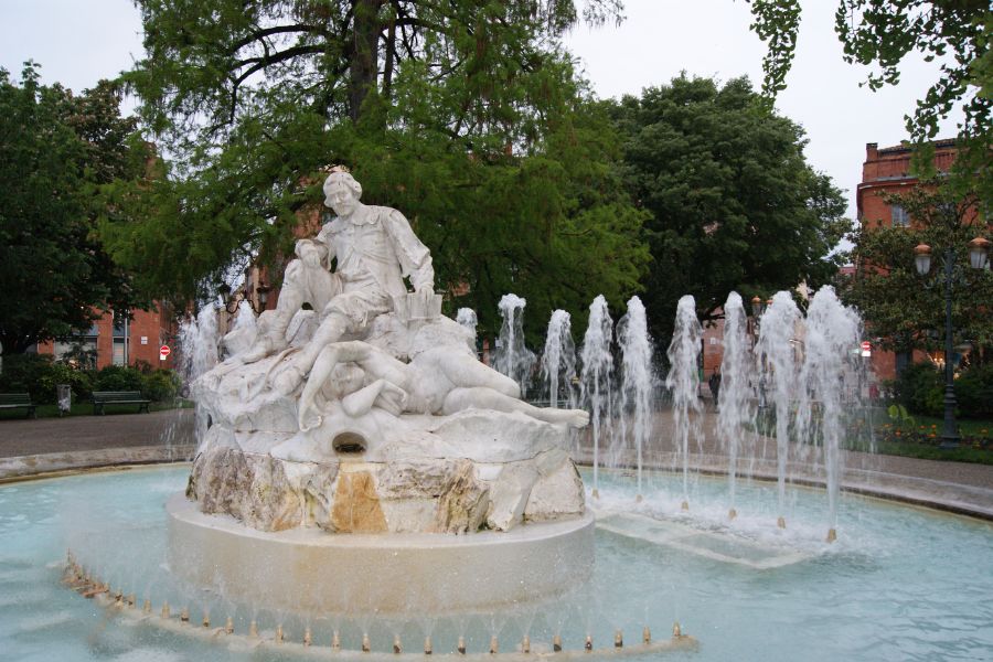 a water fountain in Toulouse, ornate marble statues sit proudly in the center of the water