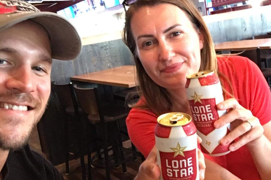 a man and a woman cheers and take a selfie with cans of lone star beer