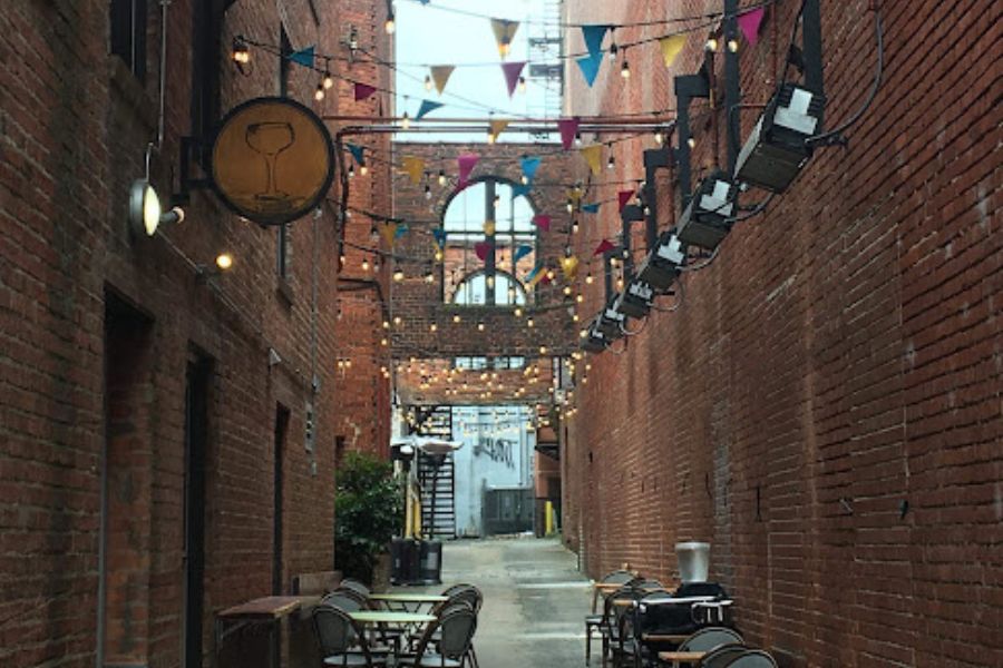 festoons light up a red brick alleyway, a handful of chairs form a bars beer garden