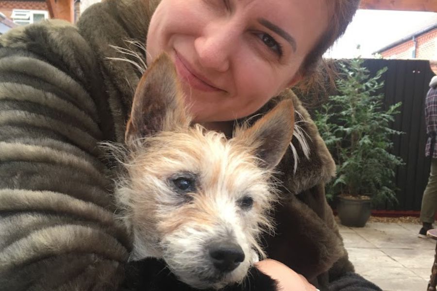 a woman hugs a small white dog