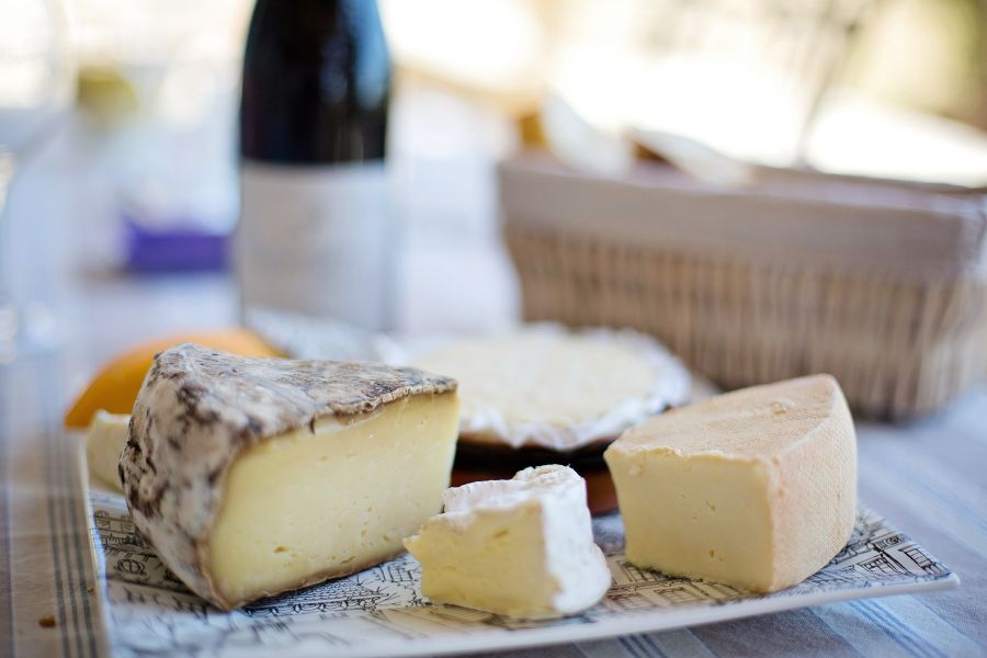 huge blocks of cheese with a blurred bottleof red wine in the rear and a basket of bread