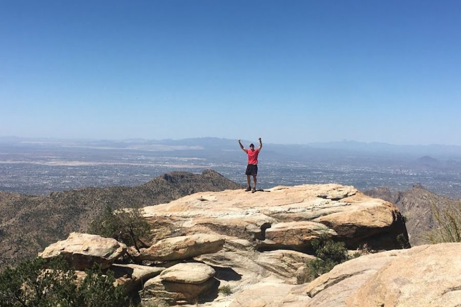 Man celebrates on a very high ledge.