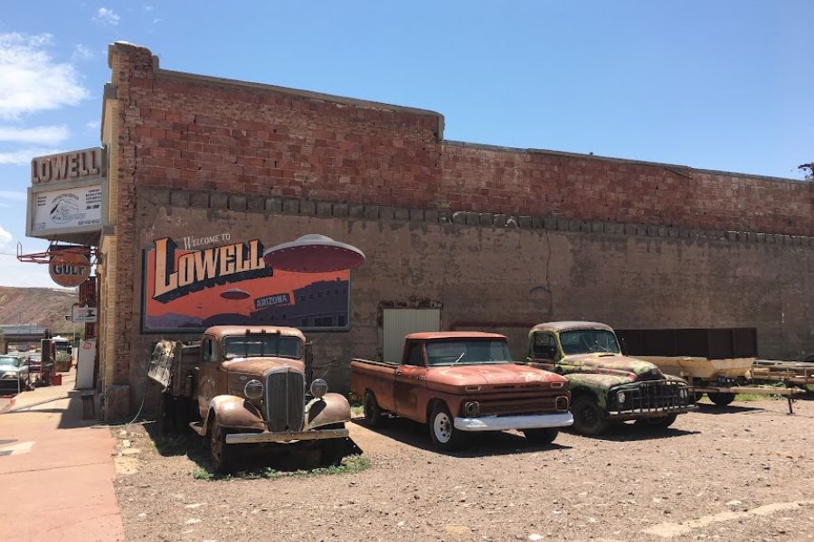 retro American cars sit in a parking lot in Lowell, AZ. Next to an old garage with a retro marquee.