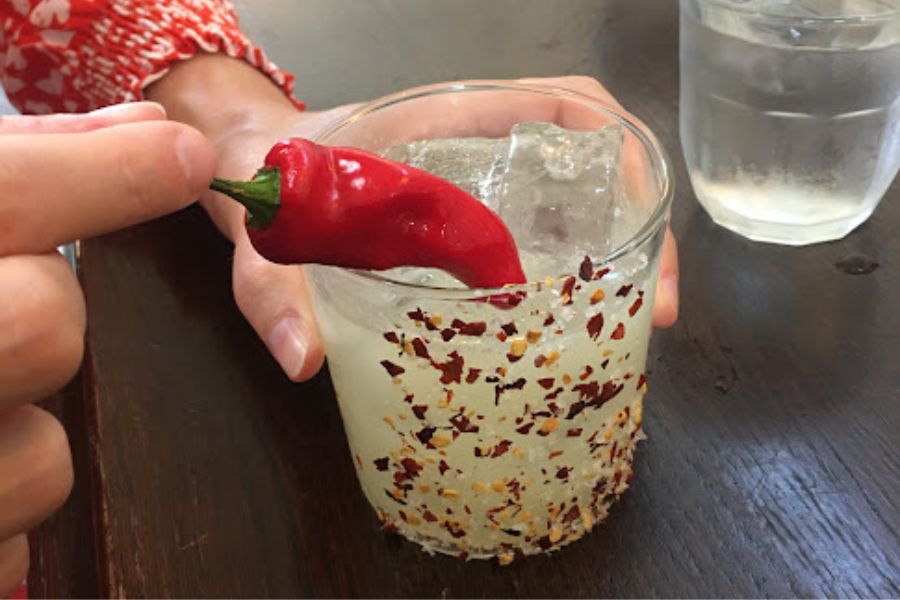 a cocktail with a large red pepper in it