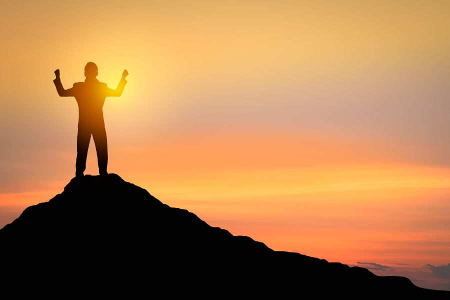 a man celebrating atop a mountain