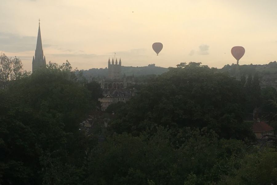 air balloons fly over the Bath city skyline at sunset