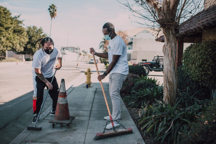 2 men brushing a sidewalk