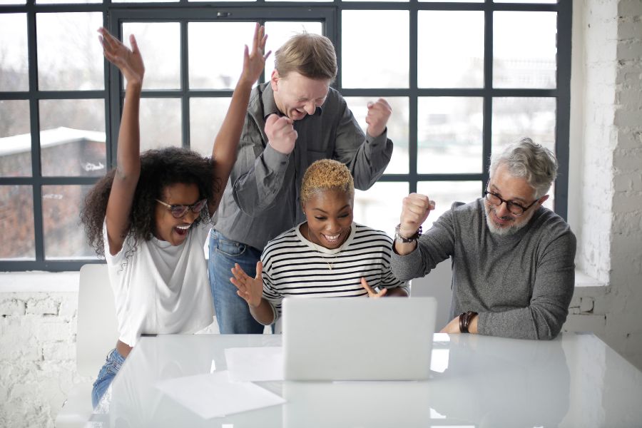 4 people celebrate in front of a laptop