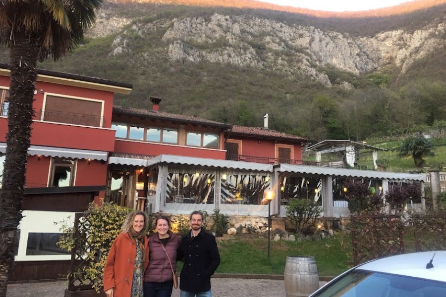 2 women and a man photo infront of a restaurant and towering hills. 