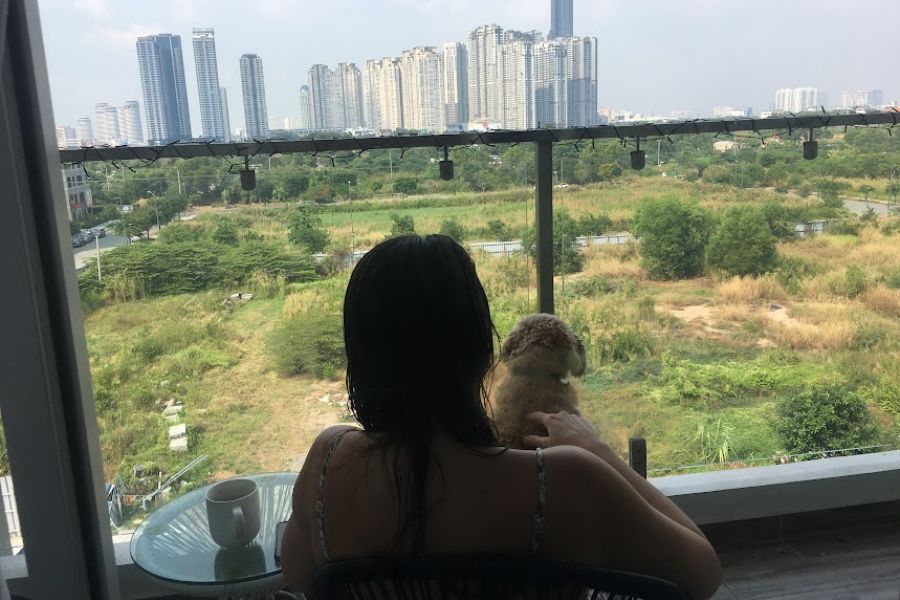 Woman and dog admire HCMC skyline from balcony apartment