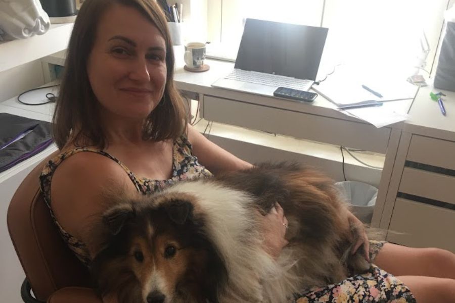 woman works at laptop with dog on lap