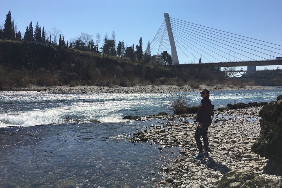 woman by river with bridge in the background